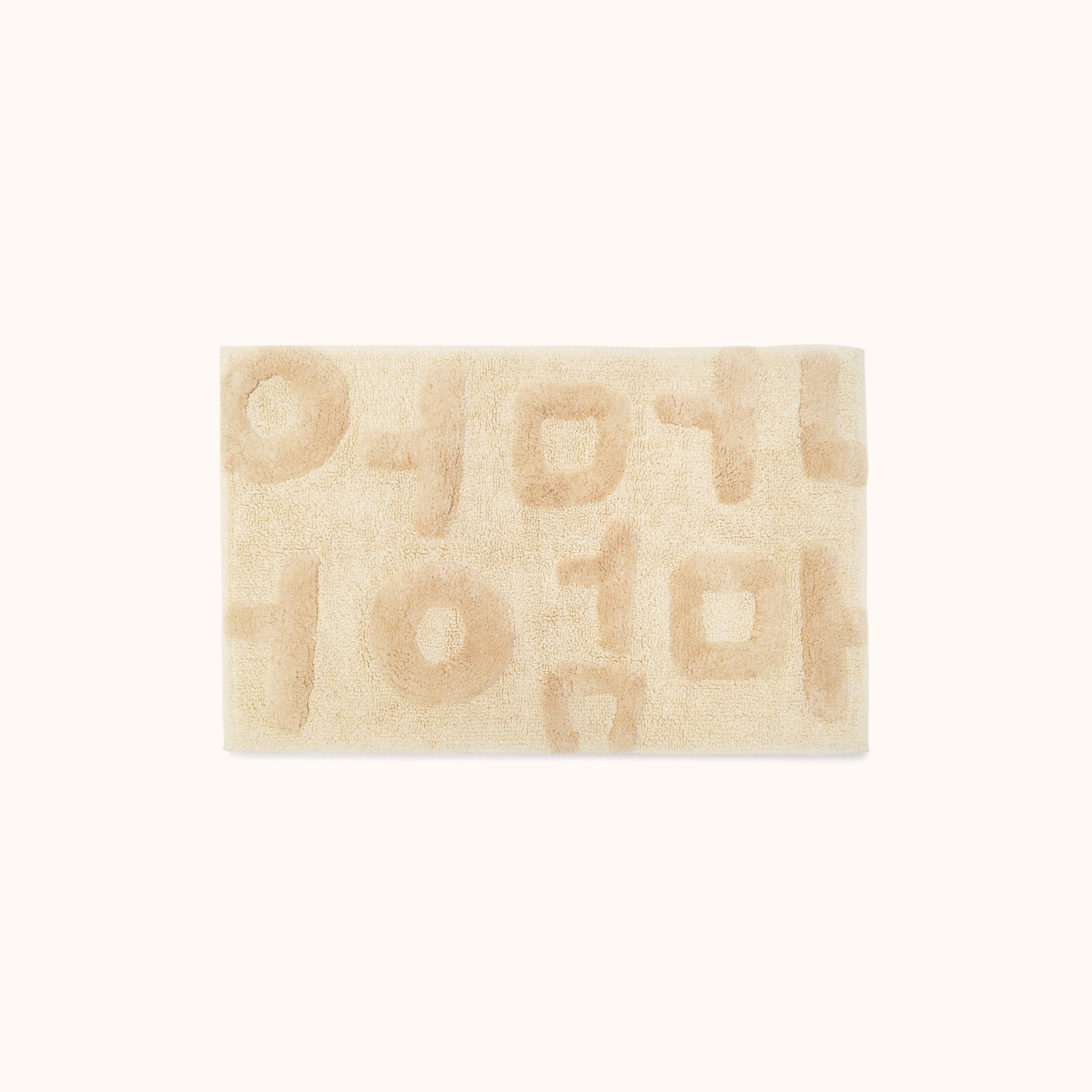 A rectangular beige bath mat with the word 'Mother' written in Korean characters, tufted in varying heights for a textured look.