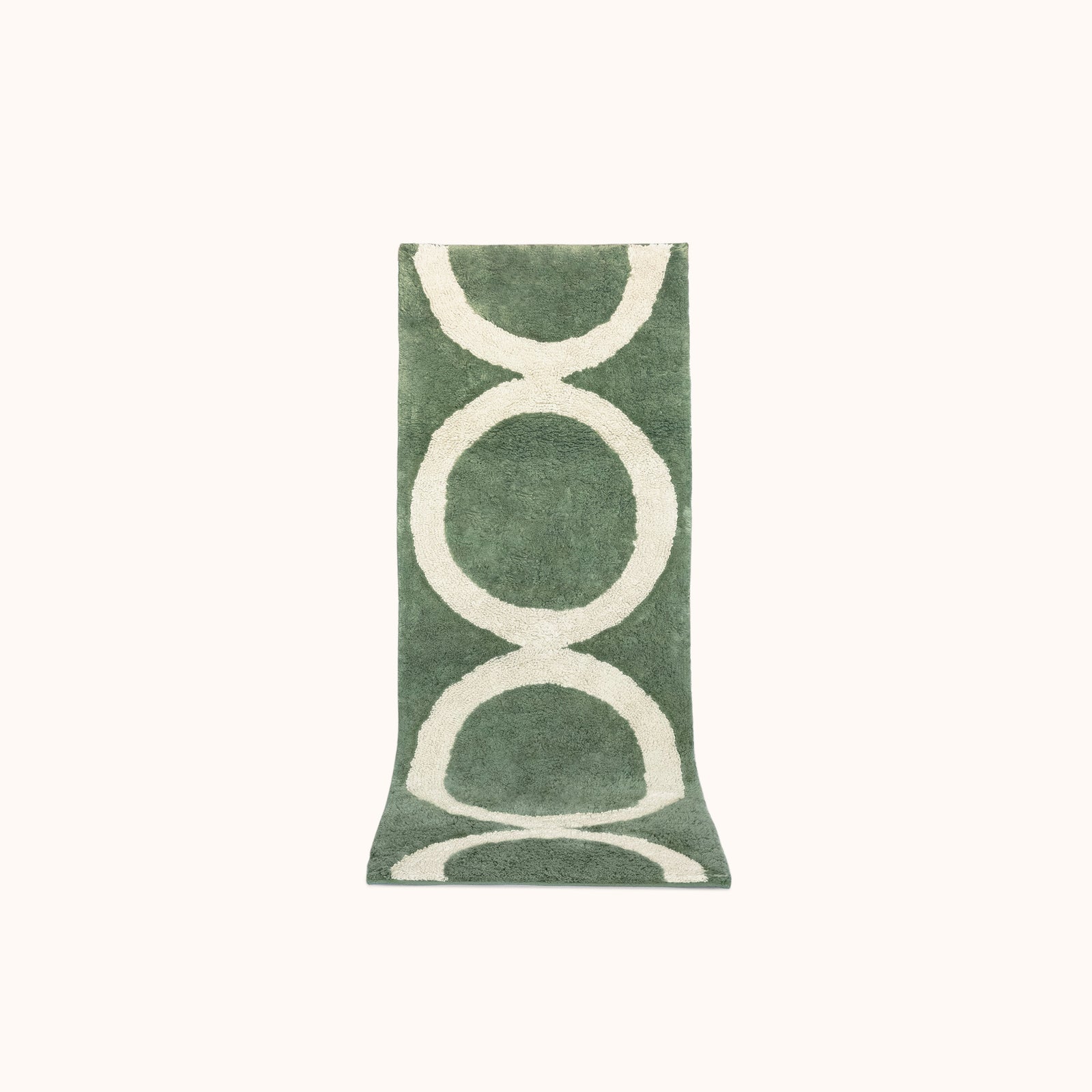 A green and tan geometric designed bath mat made of plush tufted cotton.