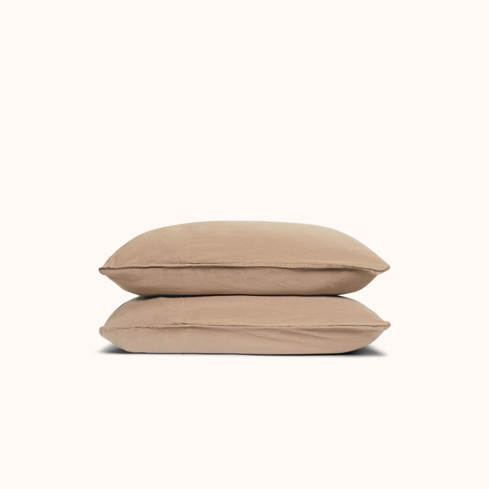 Two Dune / beige pillows stacked against a white background