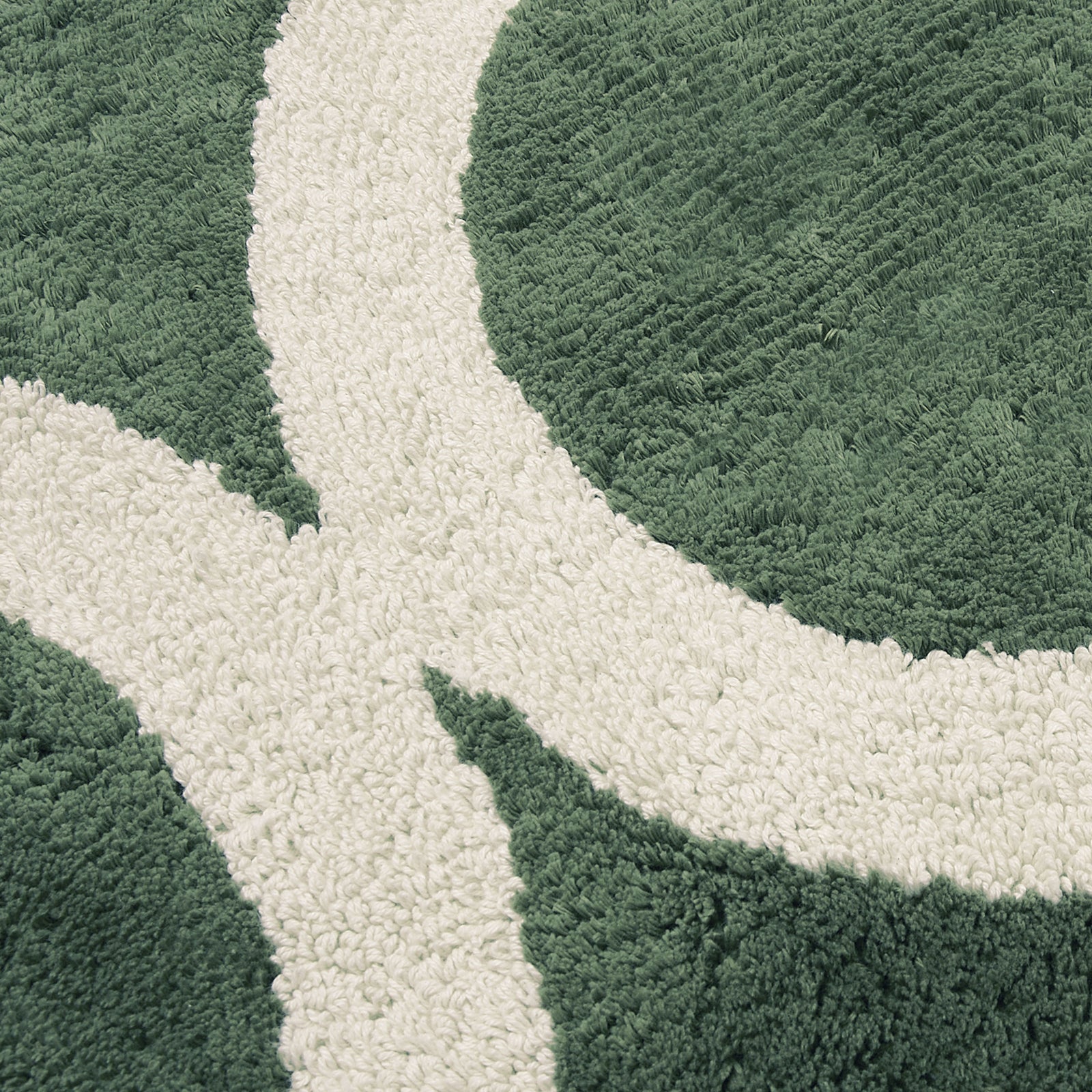 Close up of a green tufted bath runner with a tan circle geometric pattern.