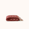 A folded red and cream blanket with textural loops and fringed edges, displayed against a natural background.