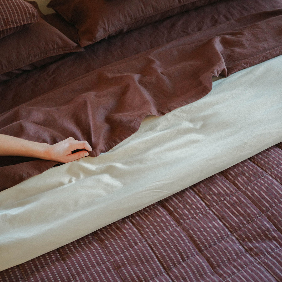 Morrow Soft Goods Pairing of Juno Check Quilt with Hemp Cotton Sheets in Brun and Duvet Cover in Oat - close lifestyle image