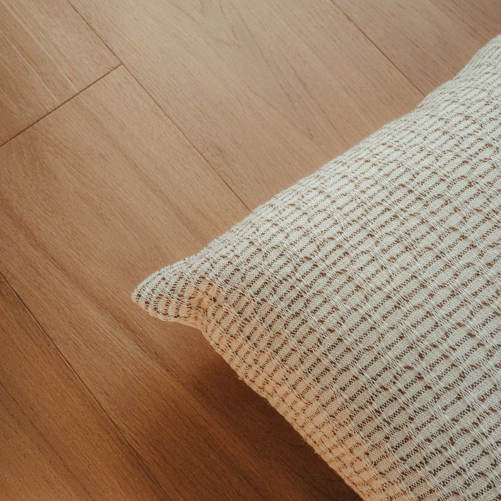 Close up of a throw pillow with a beige and brown hazelnut stripe texture.