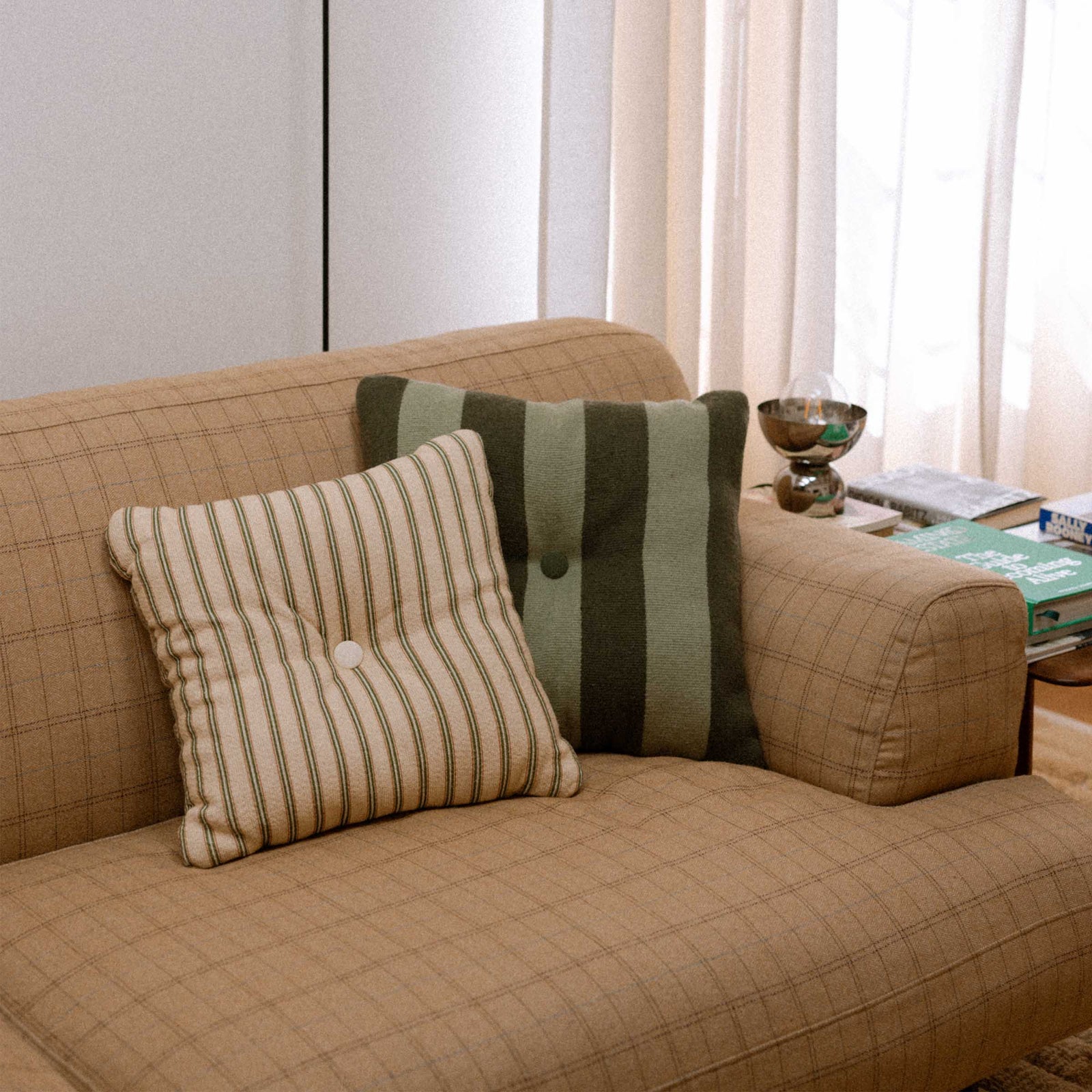 Beige sofa with green striped throw pillows in a living room setting