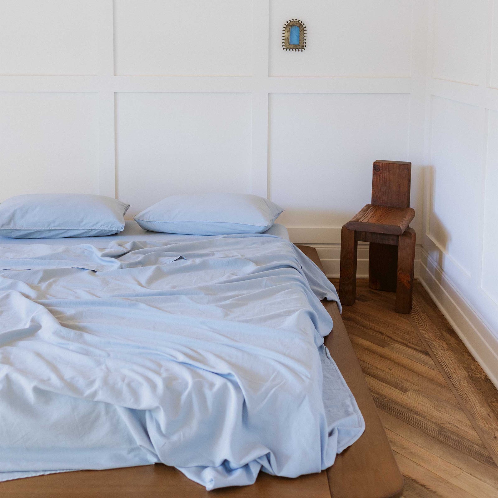 A bed dressed in Blue / Afina sheets and two pillows in a bedroom setting 
