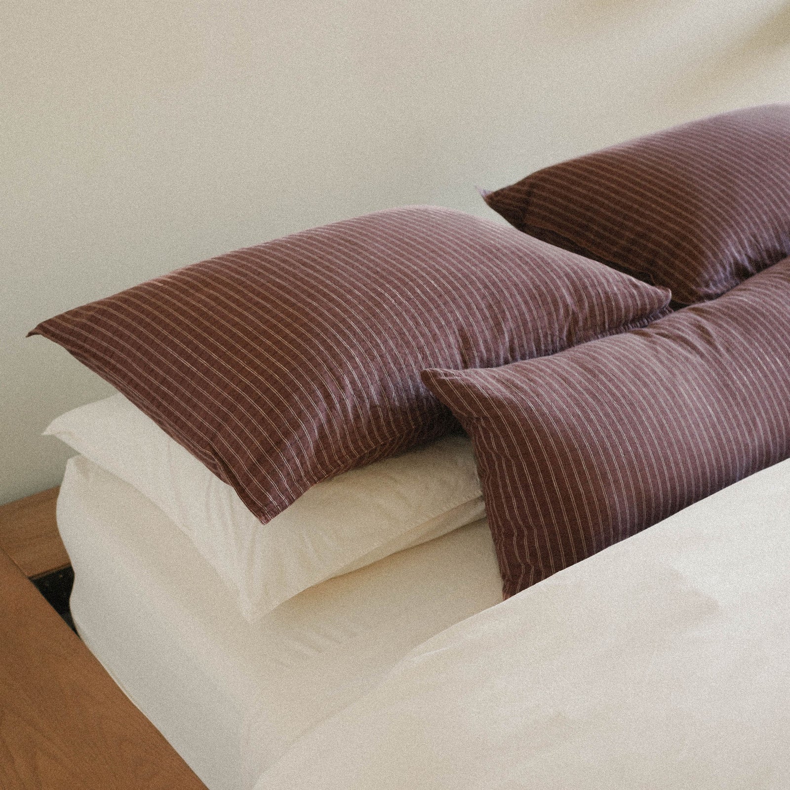 Brown striped pillows on a bed with white / cream bedding.