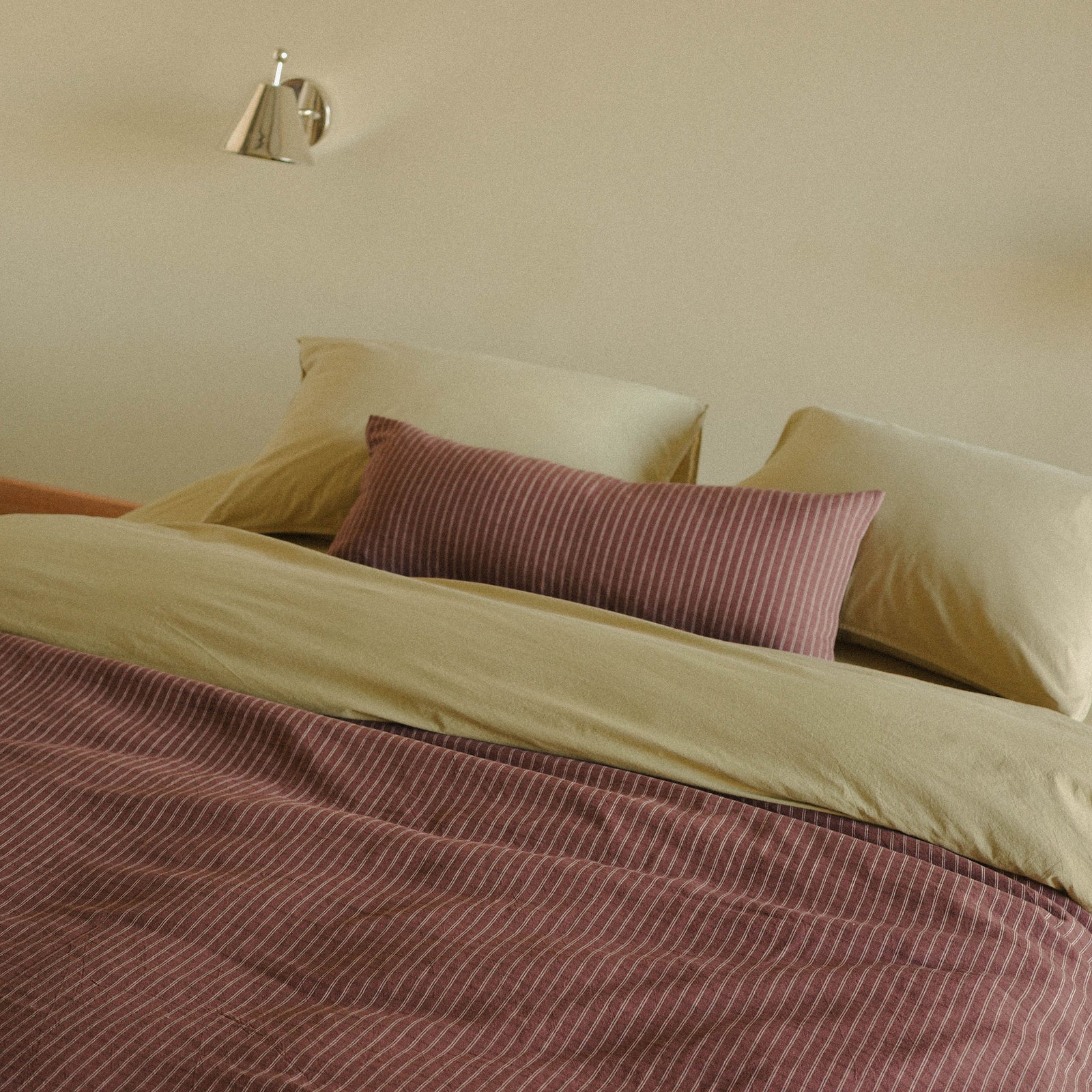 Morrow Soft Goods Juno Check Duvet and Lumbar with Organic Percale Sheets in Pale Olive on a bed