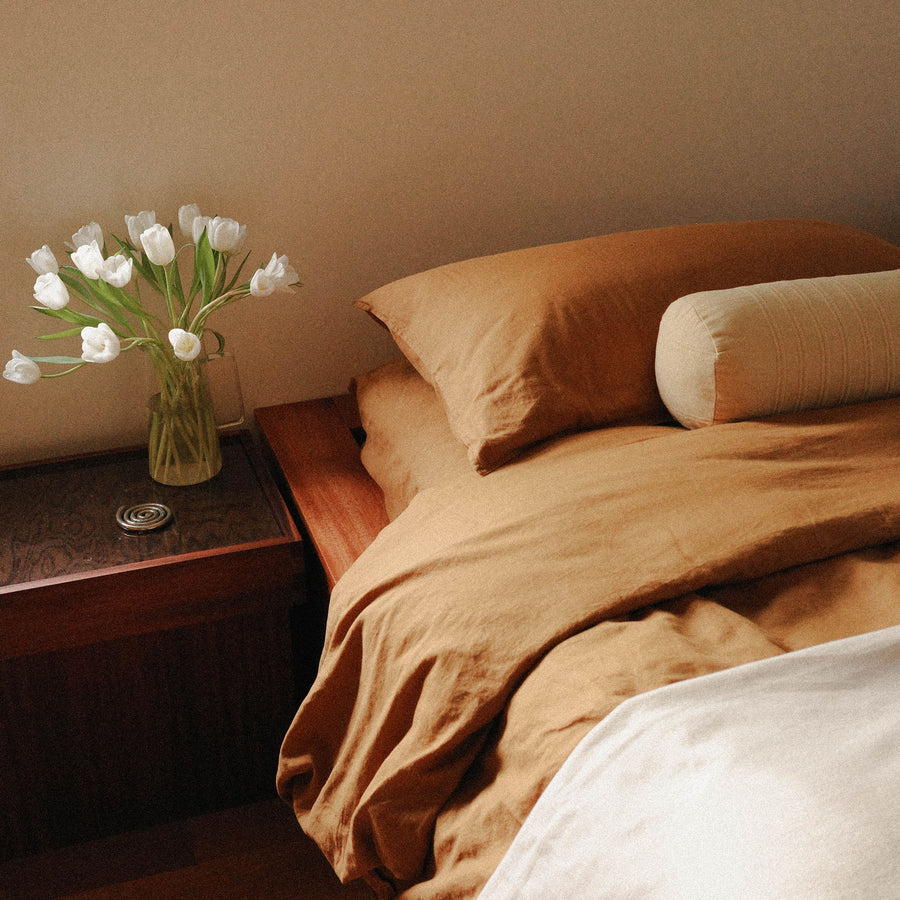 Morrow Soft Goods Hemp Cotton Duvet Cover in Willow, Marta Coverlet in White and Devi Bolster in Maiz. Bedroom Lifestyle Image Crop
