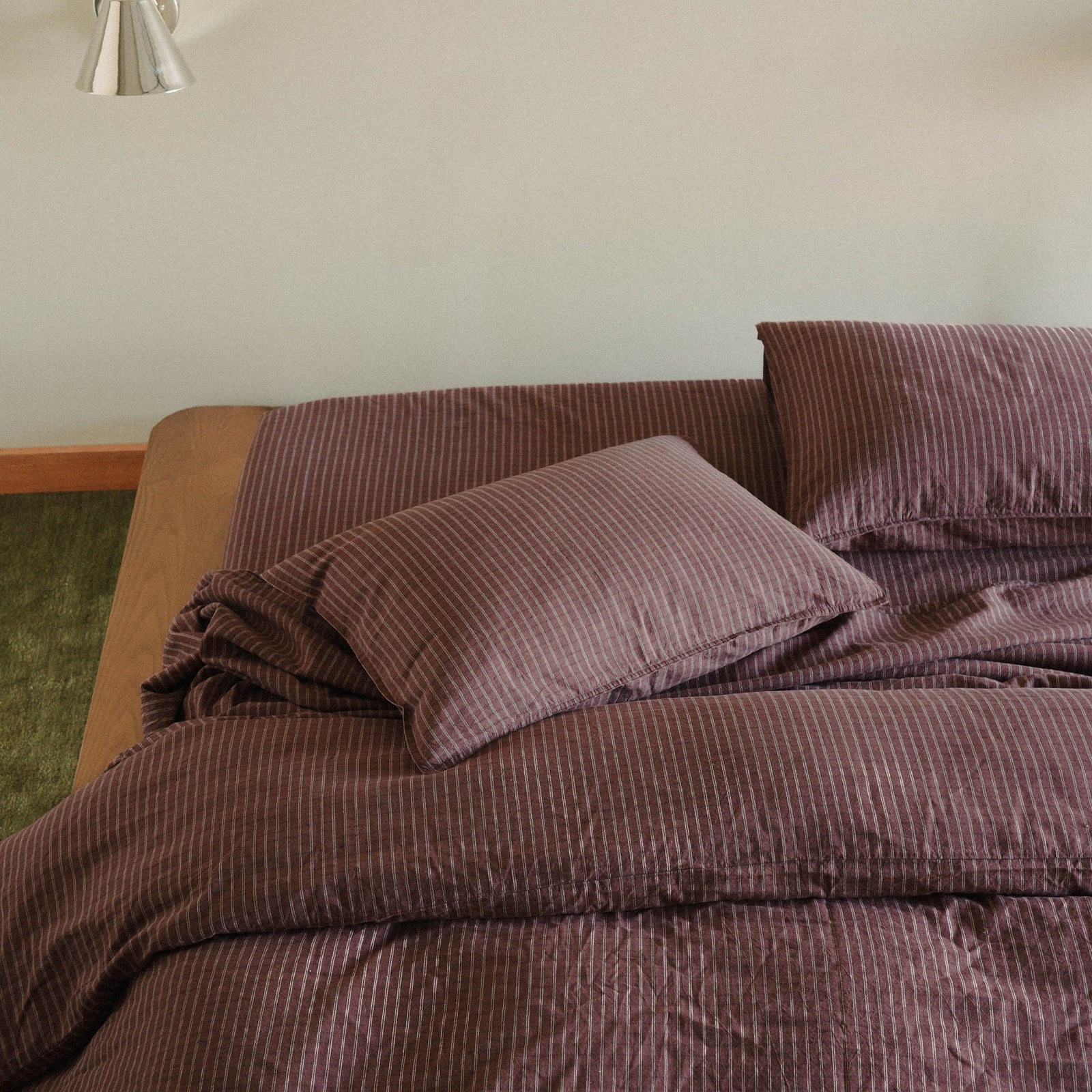 Brown striped bedspread and pillows on a wood bed