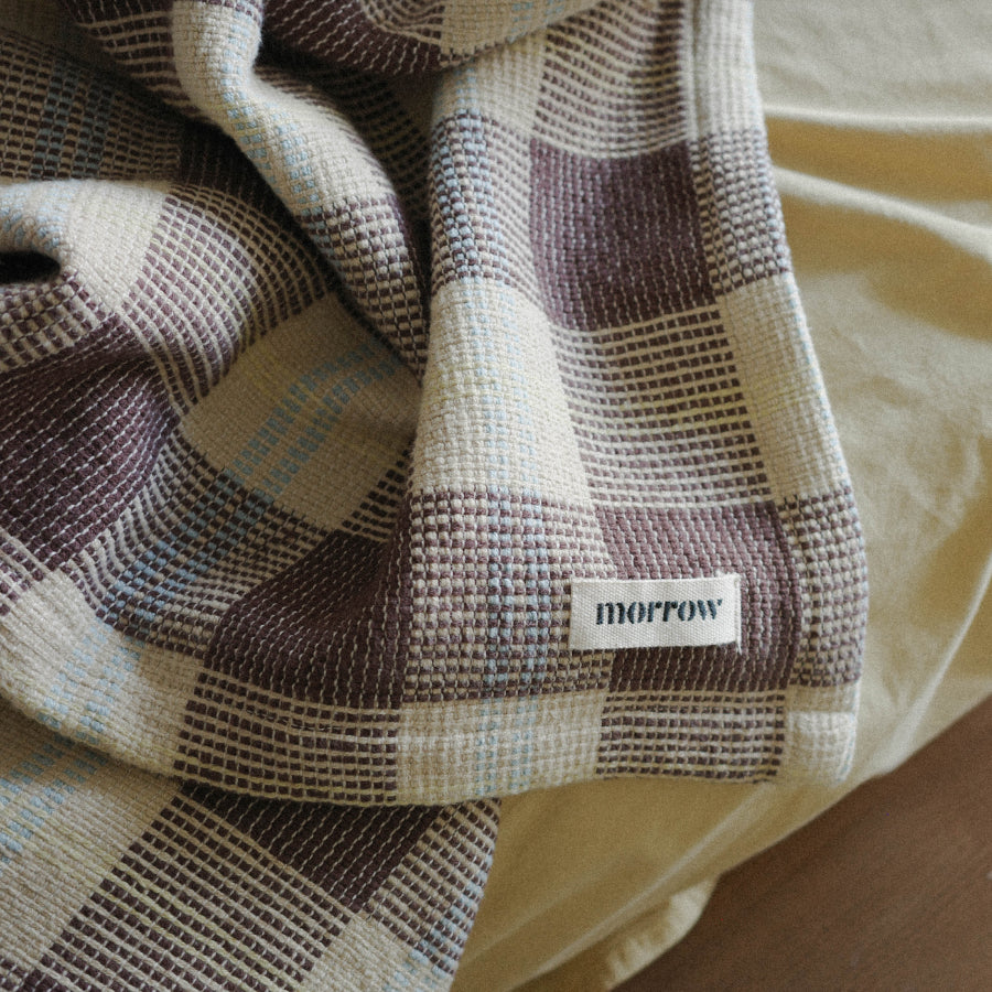 Close up detail of a brown, light yellow and blue checked blanket.