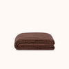 Folded brown coverlet on a white background