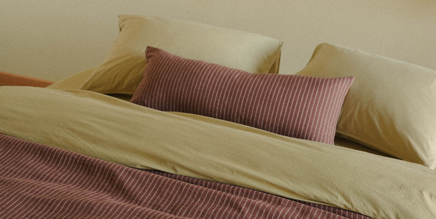 Bed with plaid bedding and pillows on a neutral background
