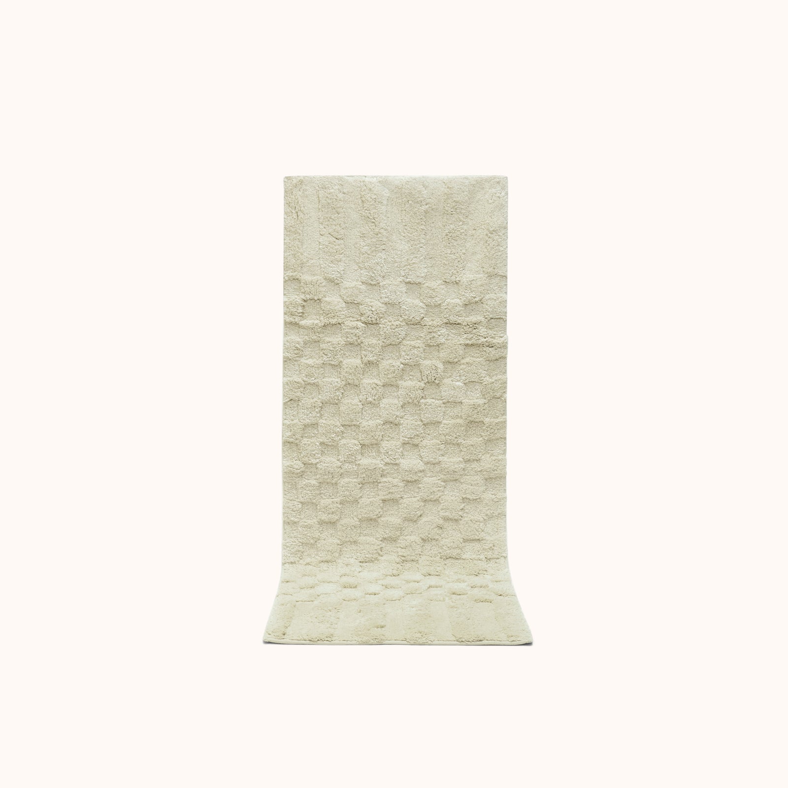 A rectangular sage green bath runner with a subtle check pattern and contrasting shag heights.