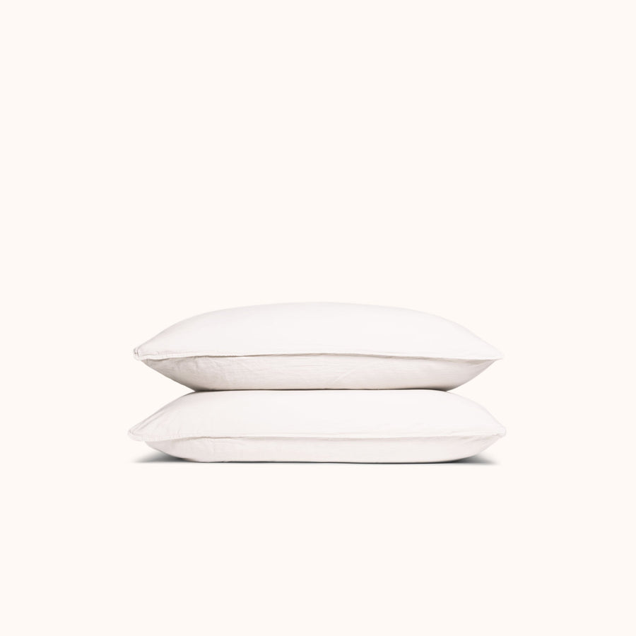 A set of white organic matte sateen pillowcases stacked neatly against a white background