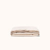 Folded Oat / cream fitted sheet made of matte sateen fabric, displayed against a white background