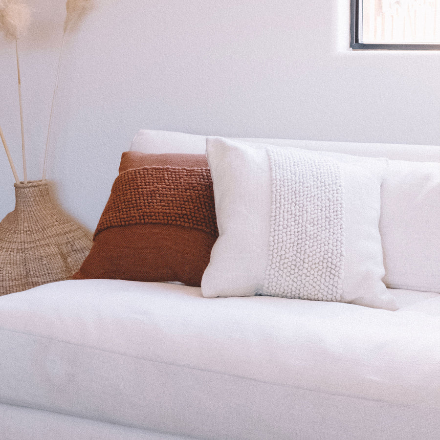 rust and white pillow on white couch