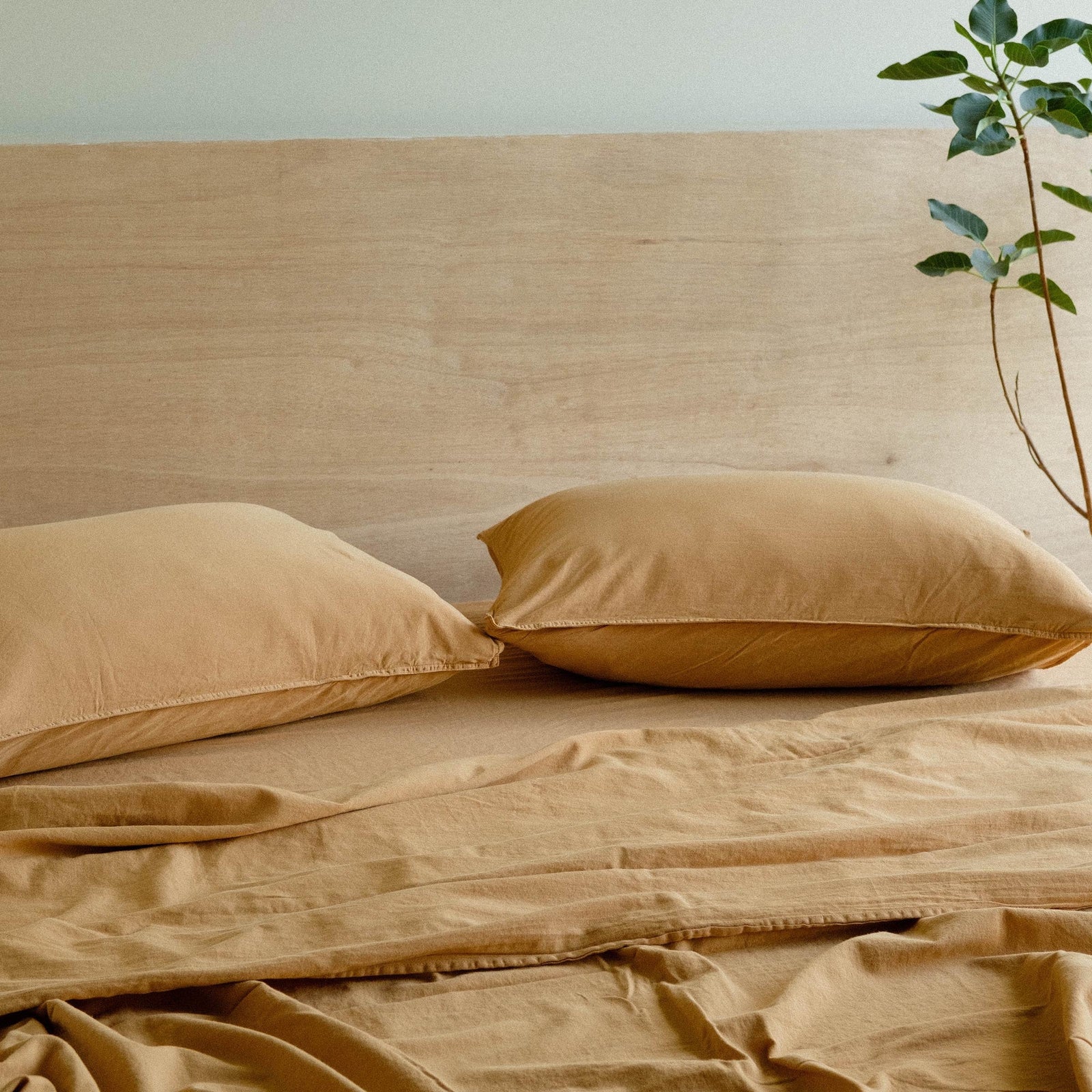 Two light camel matte sateen pillows laying flat side by side on a bed dressed with light camel matte sateen sheets 